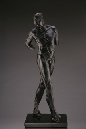 Entitled ADAM M-72, this is a photo of a fragment of a one-quarter life size bronze sculpture. Depicted is standing nude male figure missing his feet, left and right arm below the elbow. By sculptor Blake Ward.