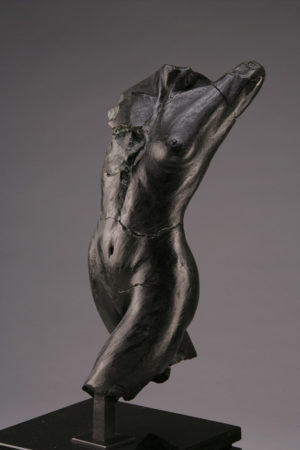 Entitled Putkimiina M-68, this is a photo of a fragment of a one-quarter life size bronze sculpture. Depicted is the torso of a nude female figure missing her legs from above the knees, both arms and head. By sculptor Blake Ward.