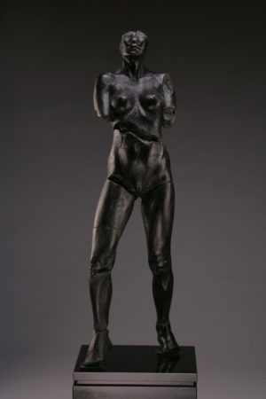 Entitled Rockeye CBU-87, this is a photo of a fragment of a one-quarter life size bronze sculpture. Depicted is standing nude female figure missing part of her feet, both arms above the elbow and her head above the nose. By sculptor Blake Ward.
