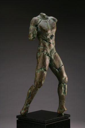 Entitled Scatmine BLU-92, this is a photo of a fragment of a one-quarter life size bronze sculpture. Depicted is standing nude male figure missing his legs at above the knee, both arms and head. By sculptor Blake Ward.