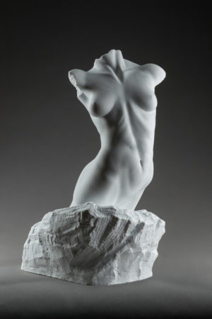 Entitled Adrianna, this is a photograph depicting a one-quarter life-size marble sculpture of a standing female figure emerging from the stone base, created by sculptor Blake Ward