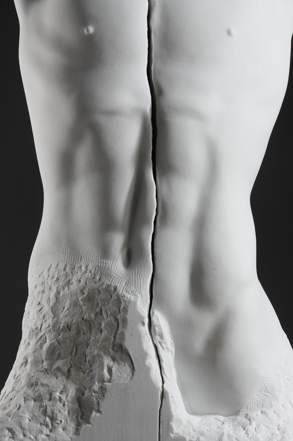 Entitled Faith, this is a photograph depicting a life-size marble sculpture of a male torso with a crack running lengthwise through the middle, created by sculptor Blake Ward