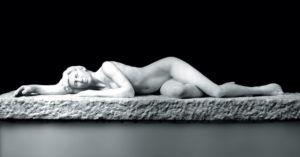 Entitled Lau, this is a photograph depicting a one-quarter life-size marble sculpture of a laying female figure, created by sculptor Blake Ward