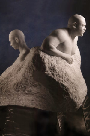 Entitled 1989: Emerging Continents this is a photograph of a large marble sculpture of two male figures, back to back, emerging from the stone base, created by sculptor Blake Ward